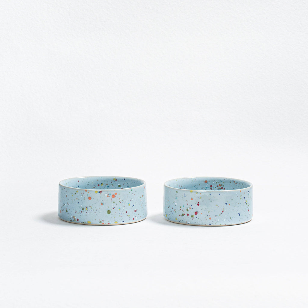 "A pair of Soft Blue New Party pet bowls in speckled stoneware with multi-colored glaze.