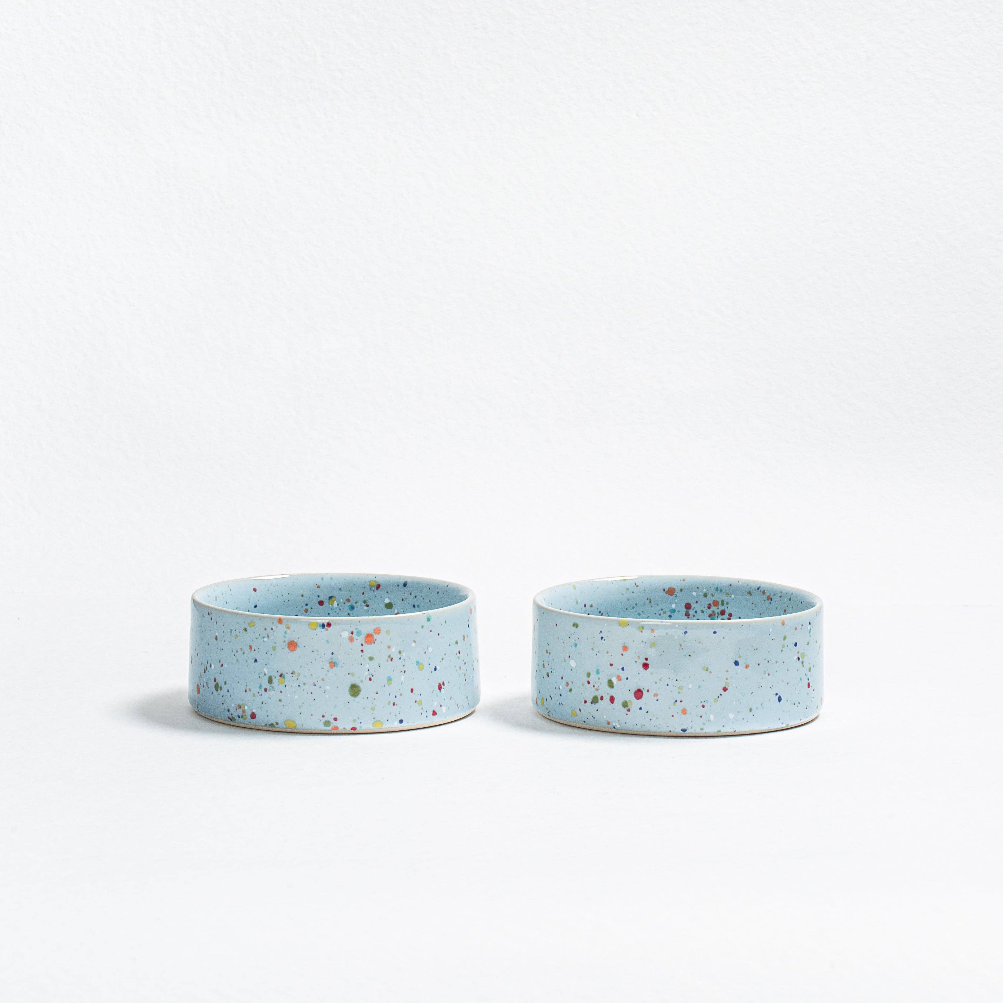 "A pair of Soft Blue New Party pet bowls in speckled stoneware with multi-colored glaze.