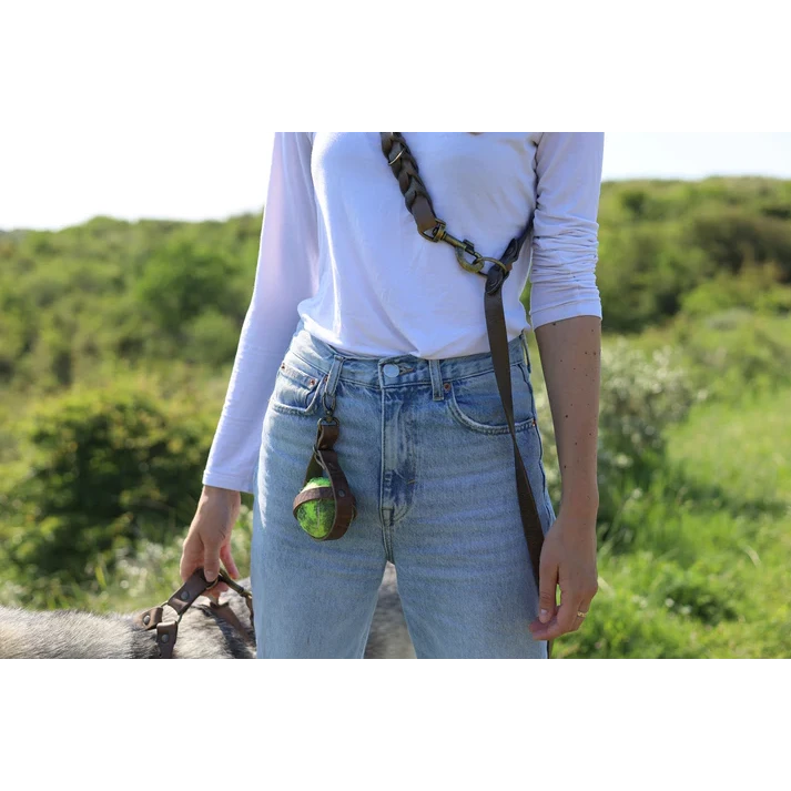 Luxury brown leather ball carrier clipped to a matching dog leash.
