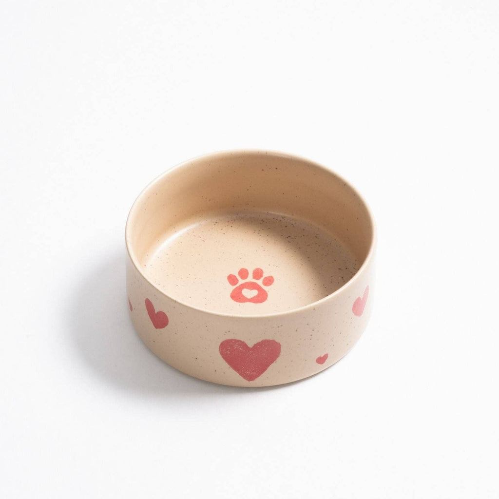 Close-up of the artisanal heart pattern on a soft beige stoneware dog bowl.