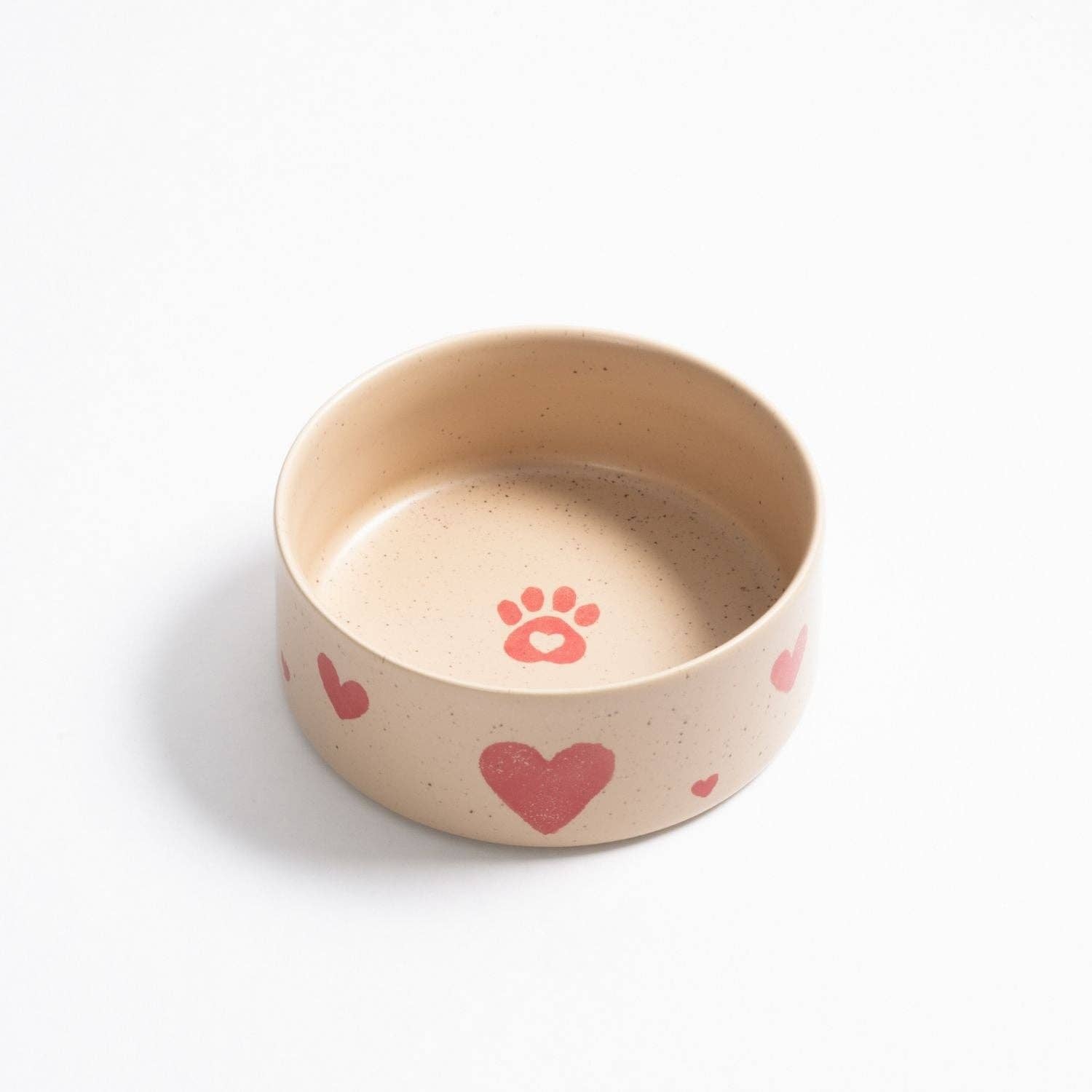 Close-up of the artisanal heart pattern on a soft beige stoneware dog bowl.