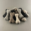 Pile of 10 cm petite felted wool dog bones in natural wool colours
