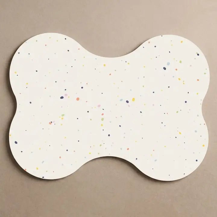 Witte gespikkelde placemat in botvorm voor huisdieren op een beige ondergrond