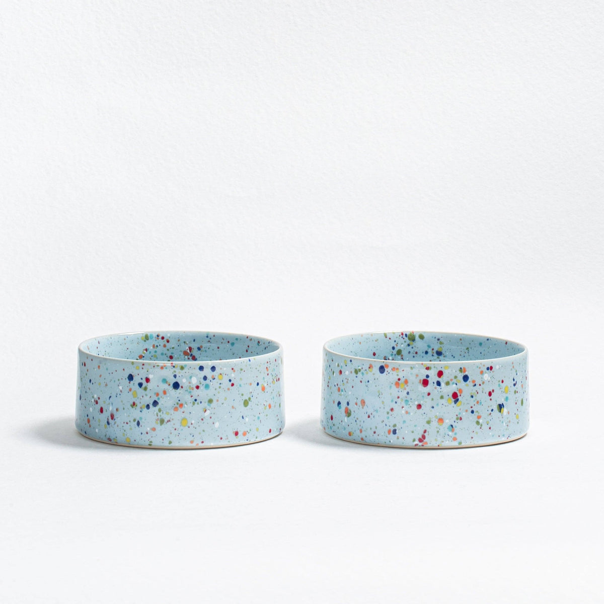 Two Soft Blue Splatter stoneware dog bowls on a white background